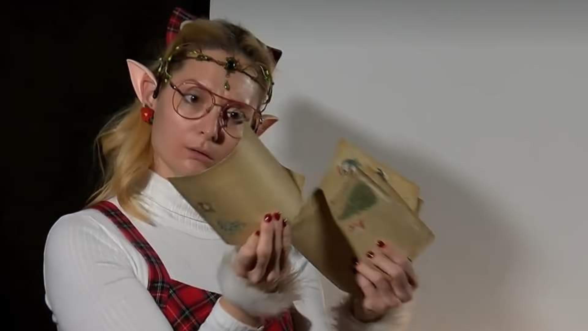 Igralka v kostumu z vilinskimi ušesi bere pisma otrok